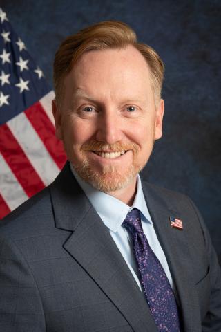 Man in suit with US flag in background.