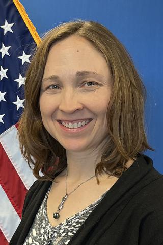 Portrait of a smiling woman in front of an American flag.