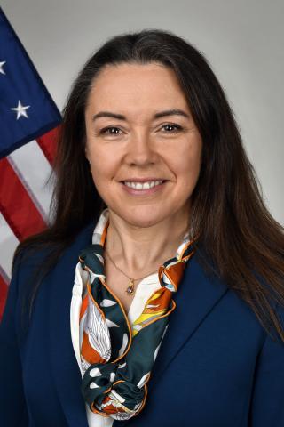 Portrait of a smiling woman in front of an American flag.