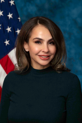 Dr. Salty, wearing a black turtleneck, with an American flag behind her.