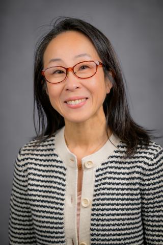 Portrait of a woman in a black and white striped blazer, smiling.