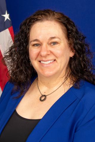 Dr. Susan Bray-Hall smiles in front of an American flag for her official portrait.