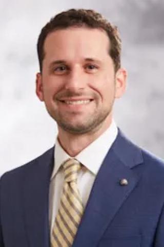 Man in blue suit, striped tie smiling for the camera.