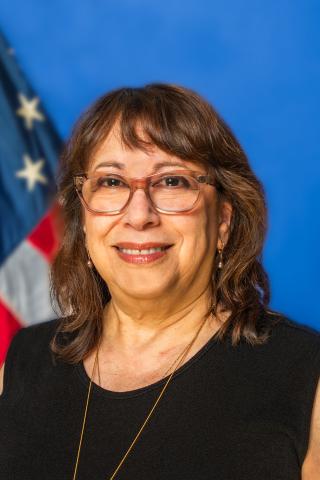 Woman smiling with American flag in the background.