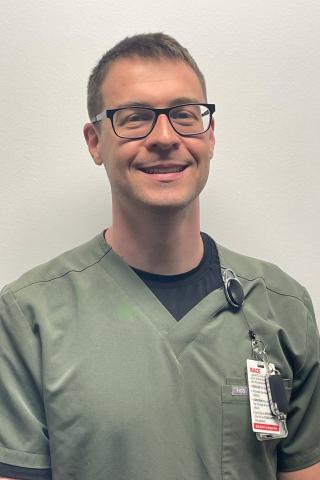 Smiling man in green scrubs with stethoscope around his neck.