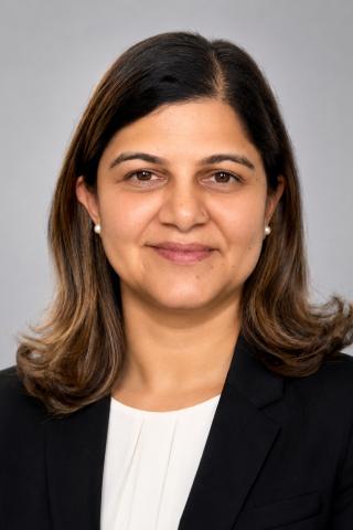 Portrait of a smiling woman in a black blazer and white shirt.