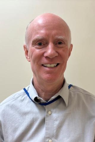 Portrait of a smiling bald man in a blue shirt.