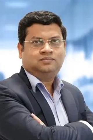 Portrait of a man in a suit with arms crossed, blurred office background.