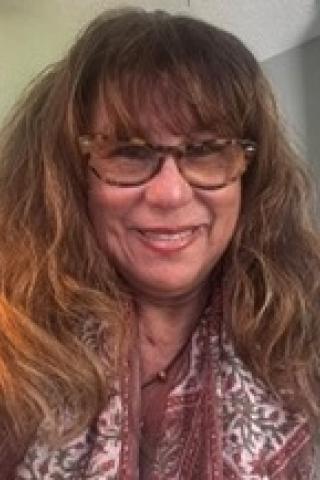 Portrait of a smiling woman with long hair and glasses.