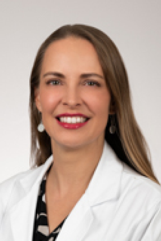 Smiling woman in white lab coat and red lipstick.