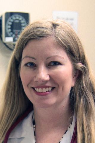 Smiling blonde woman in white lab coat and stethoscope.