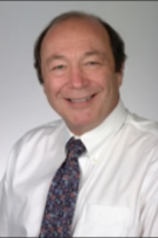 Bald man in a white dress shirt and blue tie smiling.