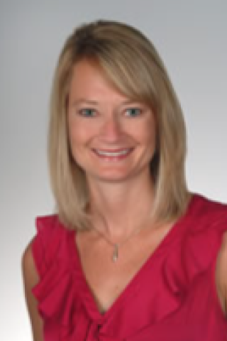 Blonde woman with short hair wearing a red blouse smiling for the camera.