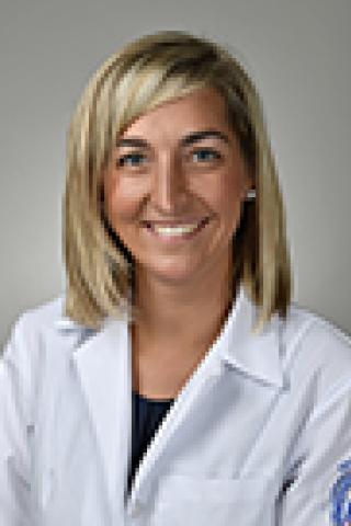 Portrait of smiling woman in white lab coat.