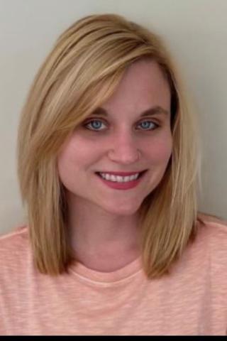 Blonde woman smiling against a plain white background.