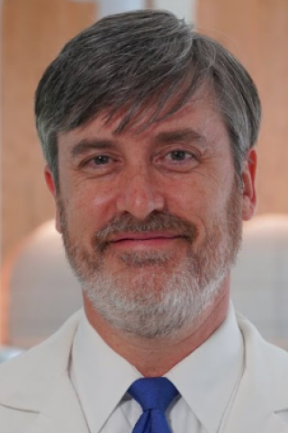 Portrait of a smiling man in a white shirt and blue tie.