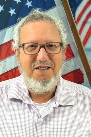 man smiling in front of flag