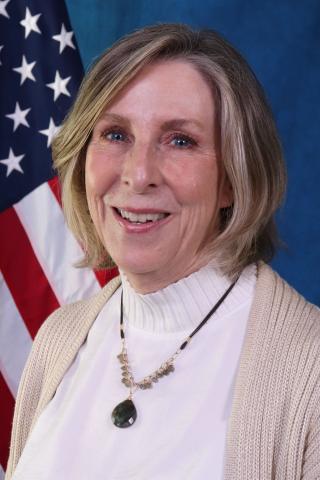 Pam McAnally smiling in front of an American flag.