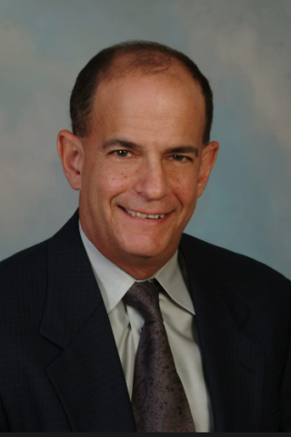 Portrait of a smiling man in a dark suit and tie.