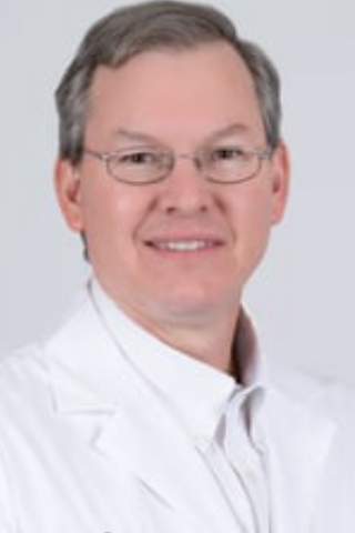 Smiling man in white lab coat and glasses, likely a doctor.