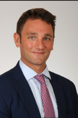 Man in navy suit and red tie smiling for the camera.
