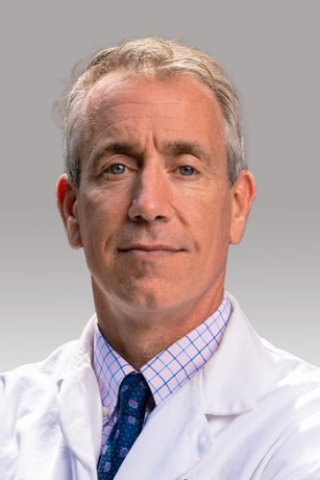 Headshot of a doctor in a white lab coat and blue tie.