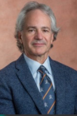 Photograph of a man in a blue suit and striped tie smiling.