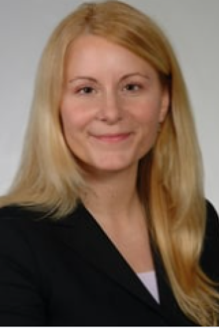 Portrait of a woman with blonde hair smiling, wearing a black blazer.