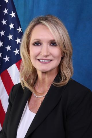 Salem VA Health Care System Executive Director, Tammy Snyder, in front of a blue background with the American flag over her left shoulder