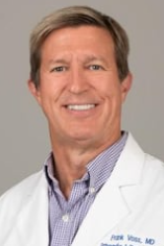 Smiling man in white lab coat with blue name tag, "John, MD".