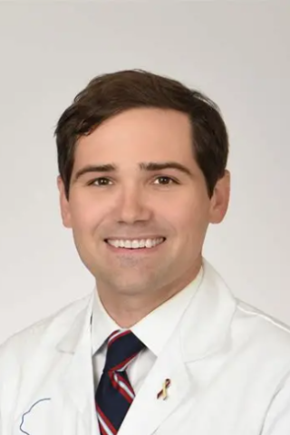 Smiling man in white lab coat and striped tie.