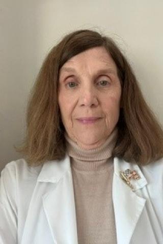 Portrait of an older woman with short brown hair wearing a white lab coat.