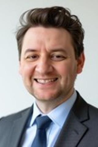 Portrait of a man in a suit and tie smiling.