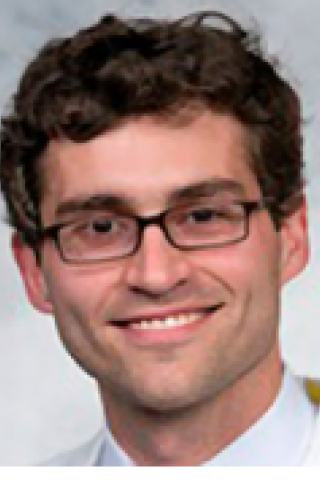 Close up of a man wearing glasses and white lab coat smiling.