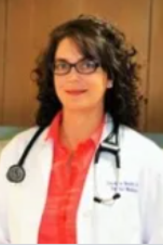 Female doctor with curly hair and glasses wearing white lab coat and stethoscope.