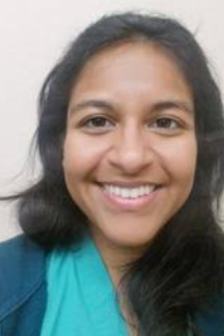 Woman with black hair and blue shirt smiling at the camera.