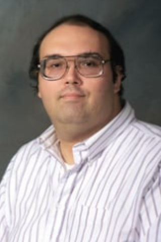 Man in white striped shirt and glasses, headshot.