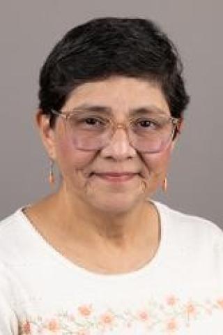 Photo of a woman with short black hair wearing glasses and a white blouse.