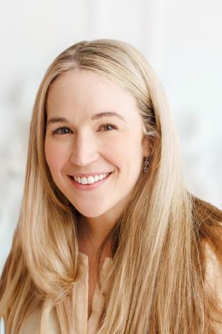 Headshot of smiling woman with long blonde hair against a white background.