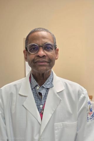 Portrait of a man in a white lab coat and glasses.