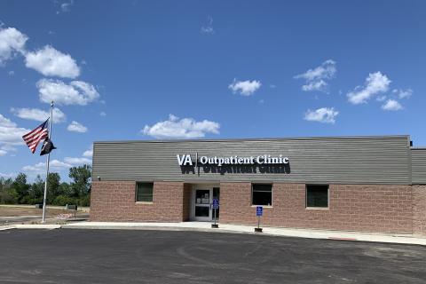 photo of a square building made of red brick and grey wood, flags and sky are visible