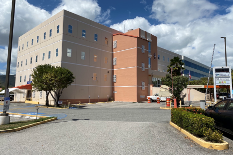 Four story beige and peach colored building with parking lot to left side of building