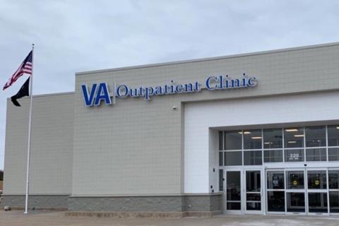 photo of a gray brick building with a wall of windows near the front entrance, the sign says VA Outpatient Clinic