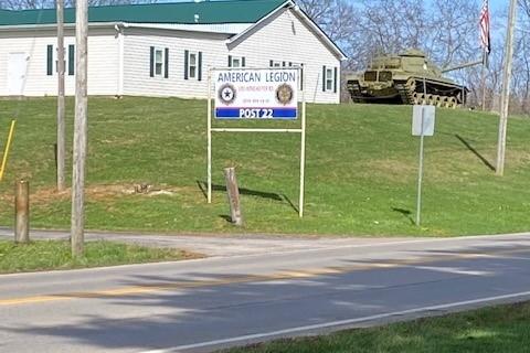 White building with green roof on hill with flag and tank.