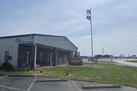 Photo of metal building with brick face and flags flying at front.