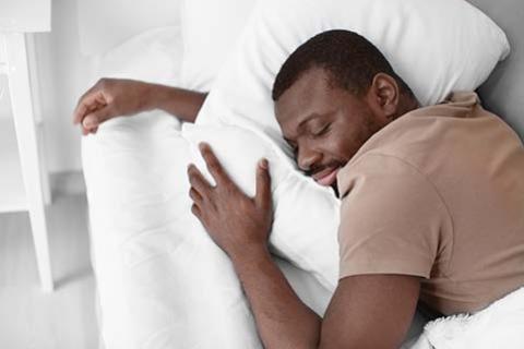 A man is sleeping and hugging his pillow
