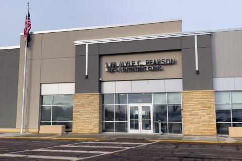 Lyle C. Pearson VA Clinic in Mankato, MN - photo of the front of a contemporary blocky glass and gray stucco building; there is an American flag to the left and a parking lot in the foreground
