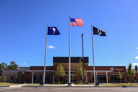 Bright blue cloudless day. Sumter Clinic with flags in foreground. 