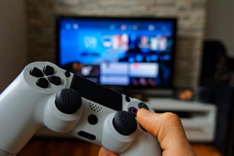 Hand holding gaming console in front of large screen television