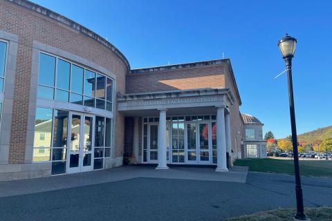 The building has large glass windows and doors and two large white pillars at the entrance. These pillars stand out against the red brick building.